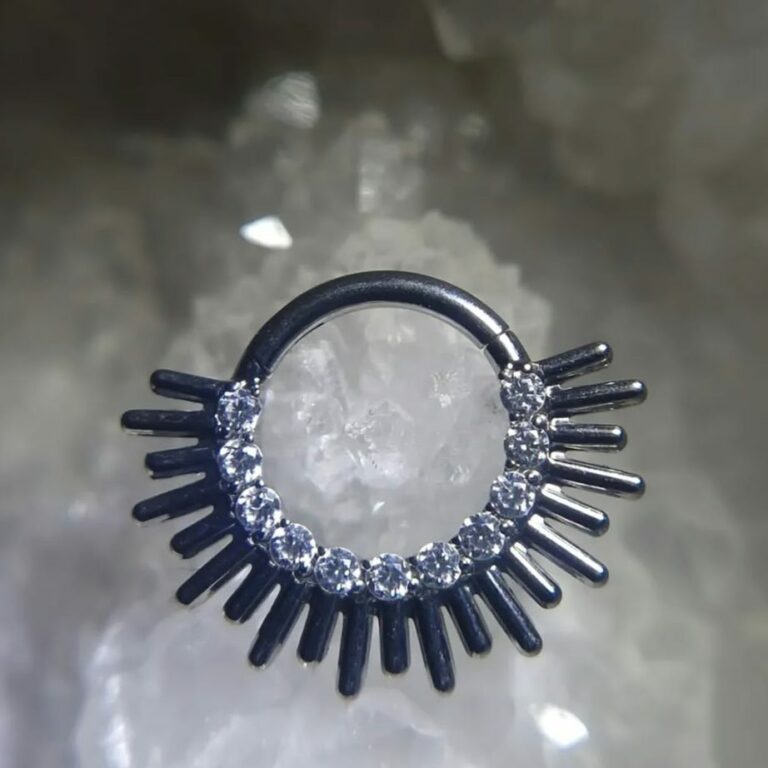 Anneau de piercing à clapet en forme de soleil, rayons métalliques et rangée de zircons blancs, disponible au salon Jolie Piqûre à Arles (couleur personnalisable)