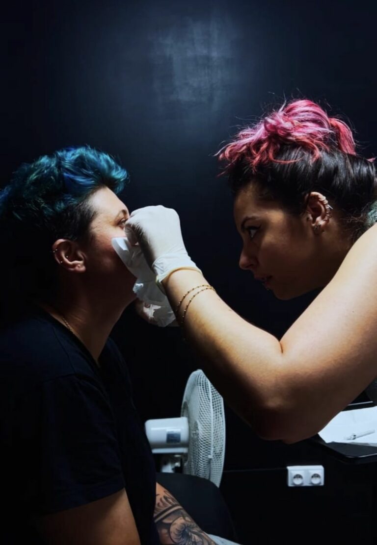 Pierceuse gantée préparant la peau d’une cliente avant un piercing du visage au salon Jolie Piqûre à Arles