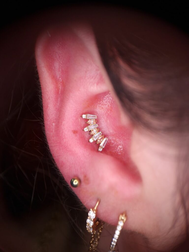 Piercing conch avec couronne de pierres baguettes, réalisé par Oc Piercing au salon Jolie Piqûre à Arles