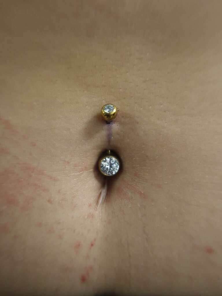 Piercing du nombril avec bijou doré et zircon, réalisé par Oc Piercing au salon Jolie Piqûre à Arles
