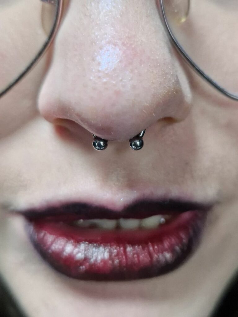 Piercing septum avec fer à cheval à billes, réalisé par Oc Piercing au salon Jolie Piqûre à Arles
